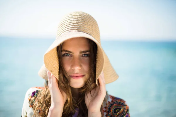 Kvinna som bär hatt stående på stranden — Stockfoto