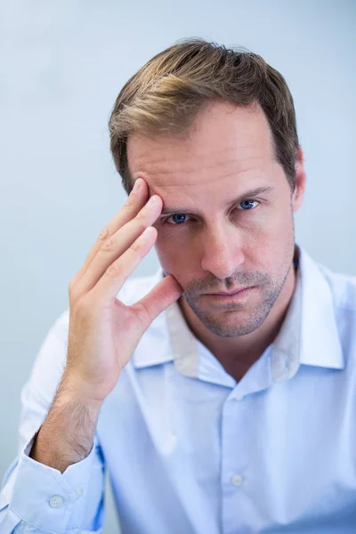 Verkrampte tandarts zit met de hand op het voorhoofd — Stockfoto