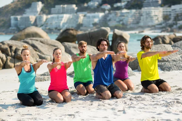 Друзья, медитирующие на коленях на пляже — стоковое фото