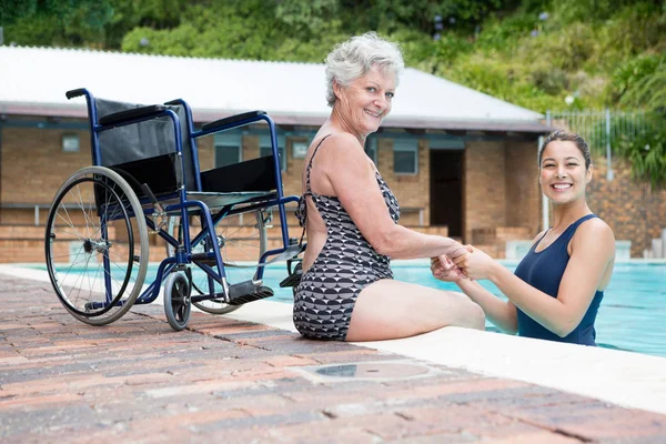 Trainer und Seniorin am Pool — Stockfoto