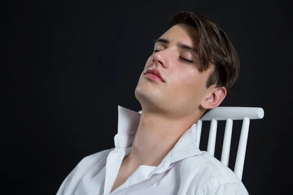 Androgynous homem posando enquanto sentado na cadeira — Fotografia de Stock