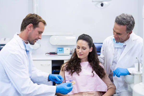 Стоматолог показывает пациенту модельные зубы — стоковое фото