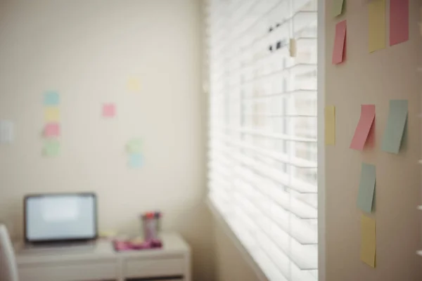 Sticky notes on wall by laptop on table — Stock Photo, Image