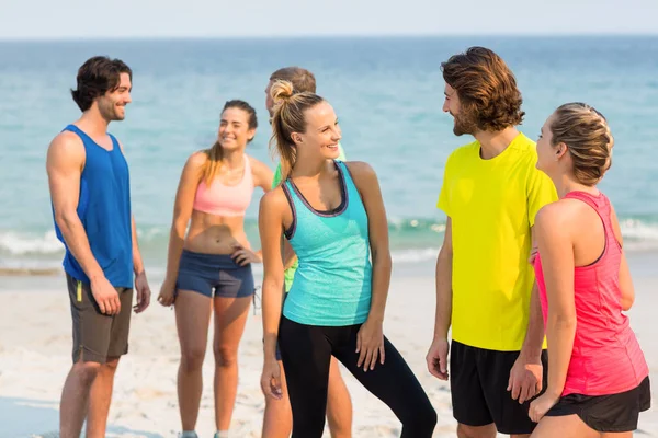 Друзья в спортивной одежде разговаривают на пляже — стоковое фото