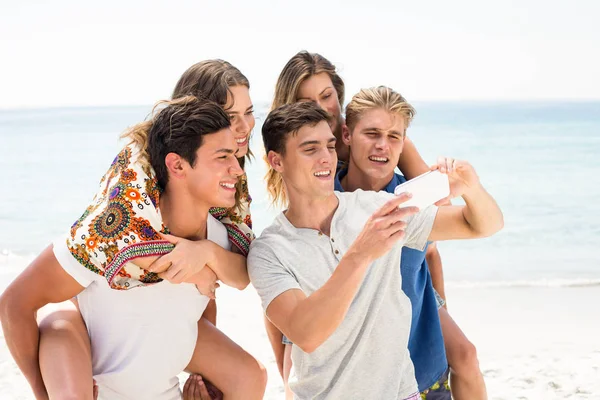 Друзья смотрят в мобильный телефон на пляже — стоковое фото