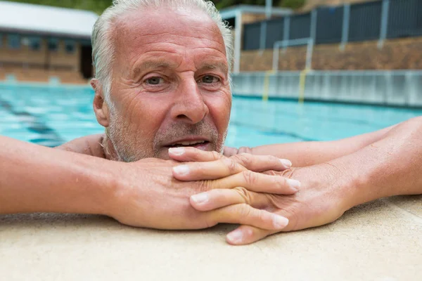 Senior mannen lutar sig på vid poolen — Stockfoto