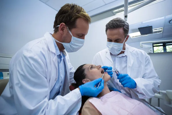 Dentistas examinando uma paciente feminina com ferramentas — Fotografia de Stock