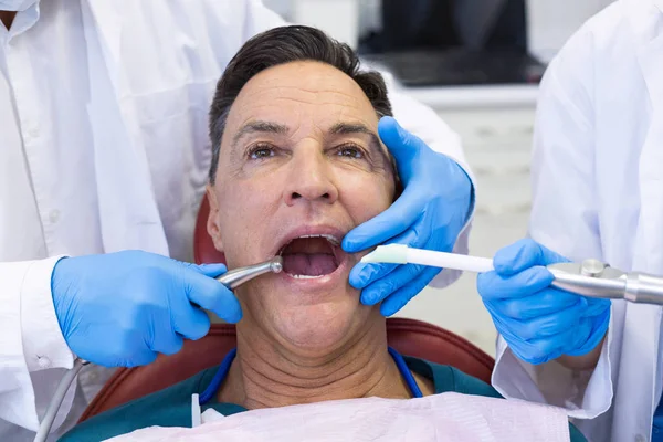 Dentista examinando um paciente do sexo masculino com ferramentas — Fotografia de Stock