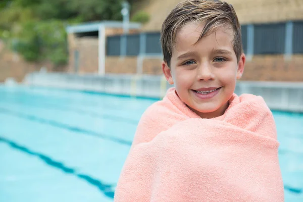 Menino envolto em toalha de pé na beira da piscina — Fotografia de Stock