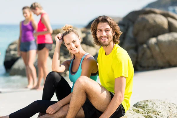 Freunde sitzen gegen Frauen am Strand — Stockfoto