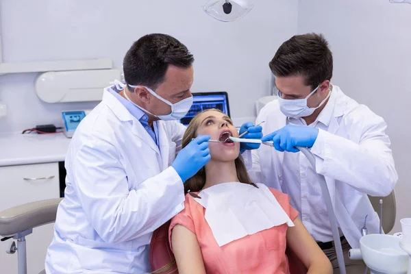 Стоматологи осматривают пациента с помощью инструментов — стоковое фото