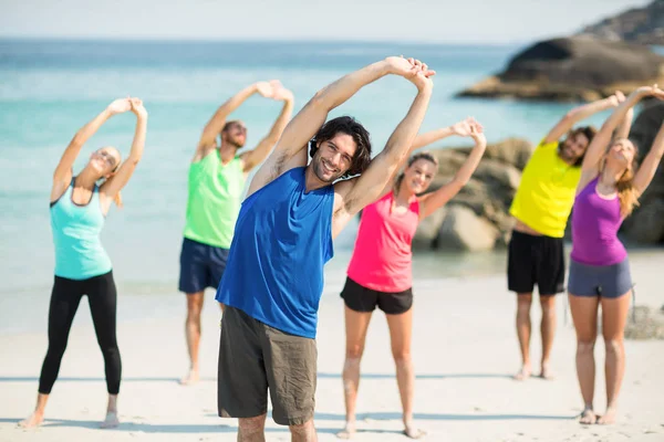 Friends exercising while standing on shore — Stock Photo, Image