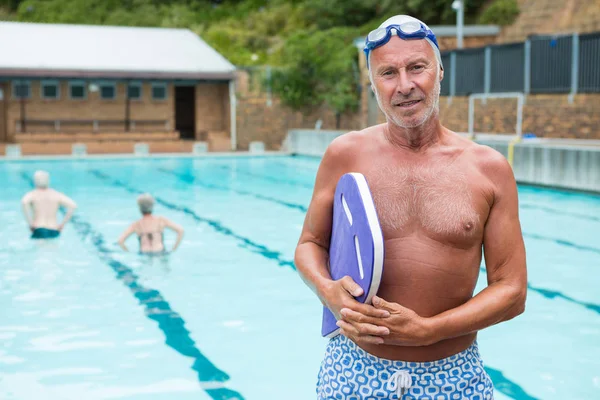 Starszy mężczyzna trzyma kickboard przy basenie — Zdjęcie stockowe