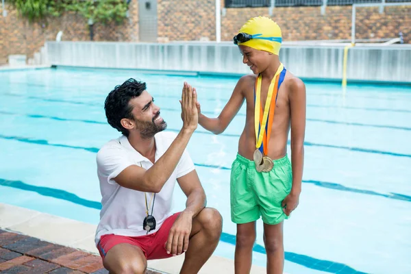 Chłopiec dając piątkę do trenera w pobliżu przy basenie — Zdjęcie stockowe