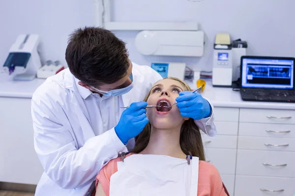 Dentista examinando uma paciente feminina com ferramentas — Fotografia de Stock