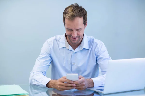 Lachende arts met behulp van mobiele telefoon — Stockfoto