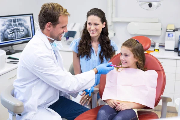 Dentista que ayuda a un paciente joven a cepillarse los dientes — Foto de Stock