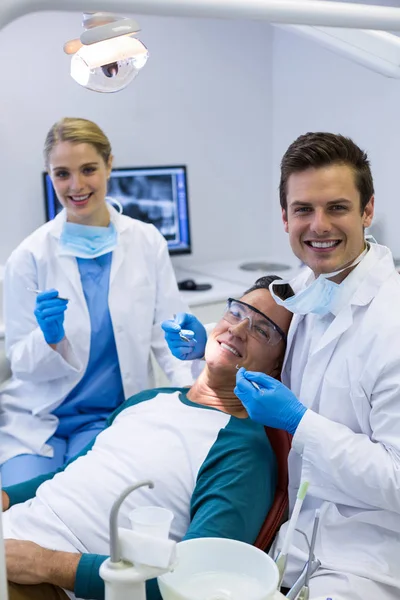 Стоматологи осматривают пациента с помощью инструментов — стоковое фото