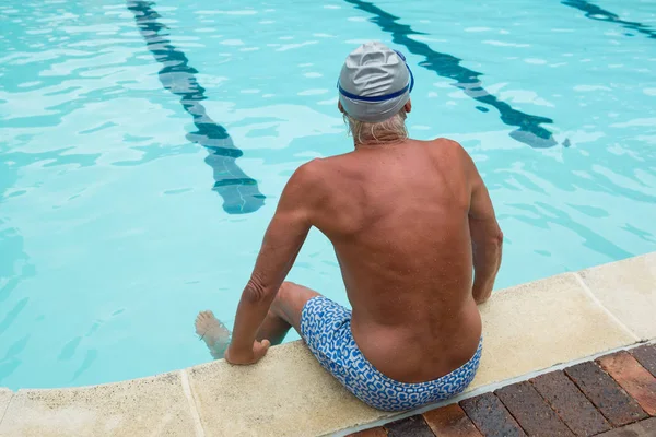 Uomo anziano seduto a bordo piscina — Foto Stock