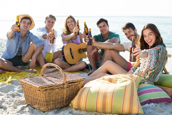 Amis prenant des boissons tout en étant assis à la plage — Photo