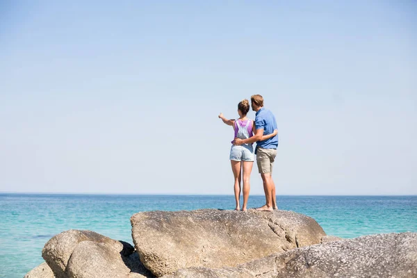 Pareja de pie sobre roca por mar — Foto de Stock