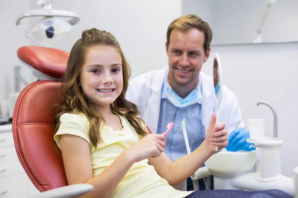 Junge Patientin hält Spiegel in Zahnklinik — Stockfoto
