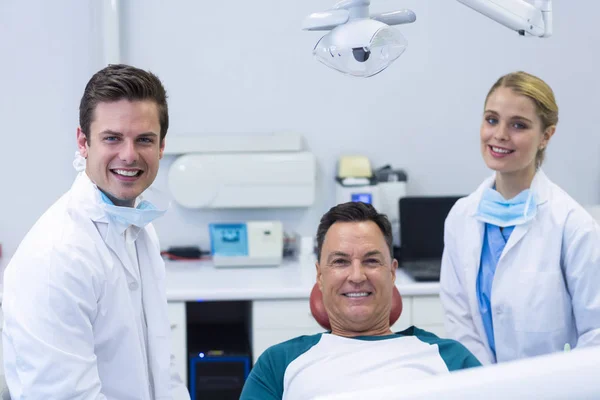 Dentistas sonrientes y paciente masculino — Foto de Stock