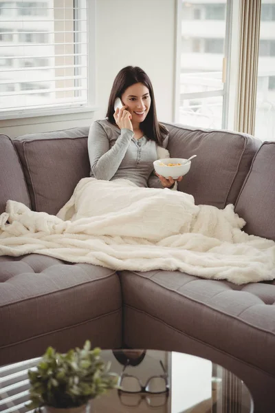 Woman talking on phone while eating breakfast — Stock Photo, Image