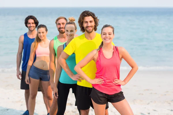 Vänner i sportkläder stående vid stranden — Stockfoto