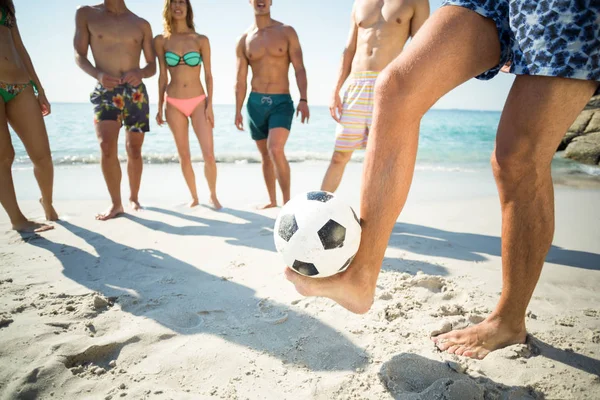 Hombre balanceando pelota de fútbol contra amigos — Foto de Stock