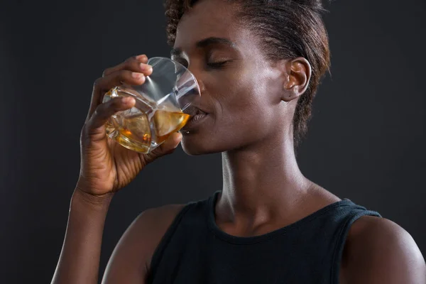 Androgyniczny człowiek picie whisky ze szkła — Zdjęcie stockowe