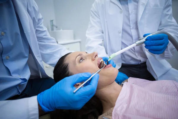 Dentista examinando uma paciente feminina com ferramentas — Fotografia de Stock