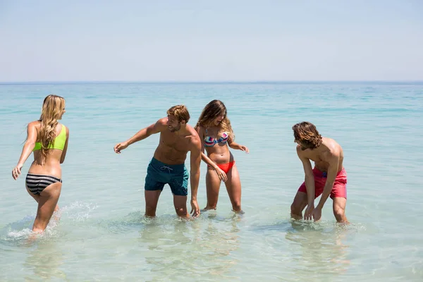 Fröhliche junge Paare genießen im Meer — Stockfoto