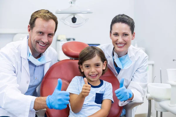 Dentists and young patient showing thumbs up — Stock Photo, Image