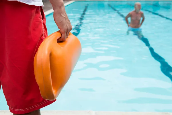 Lifeguard holding rescue buoy at poolside — Stock Photo, Image