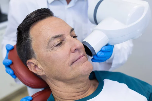 Dentiste examinant un patient masculin avec un outil dentaire — Photo