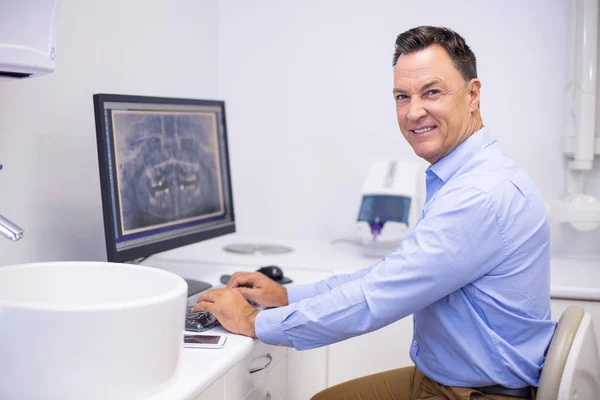 Dentist examining x-ray report on computer — Stock Photo, Image