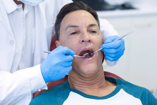 Dentista examinando a un paciente masculino con herramientas —  Fotos de Stock