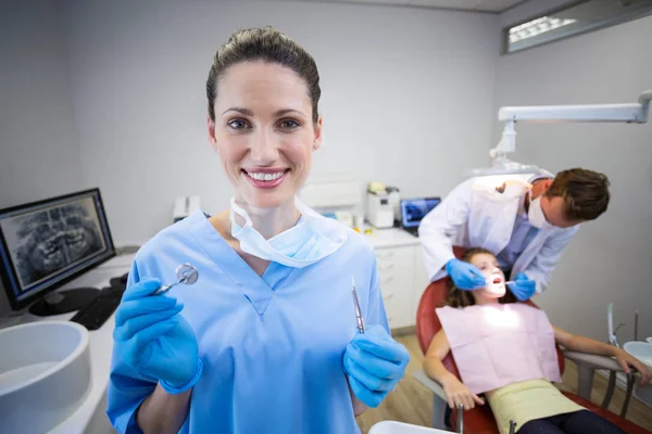 Enfermeira segurando ferramenta dentária na clínica — Fotografia de Stock