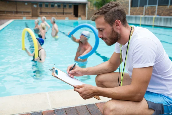 Schwimmtrainer schreibt auf Klemmbrett — Stockfoto