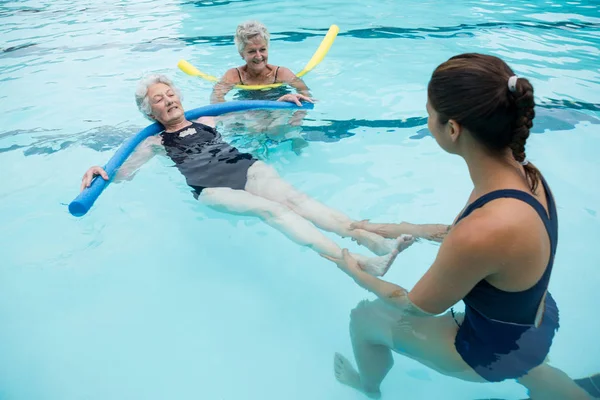 Treinador feminino ajudando mulheres idosas na piscina — Fotografia de Stock