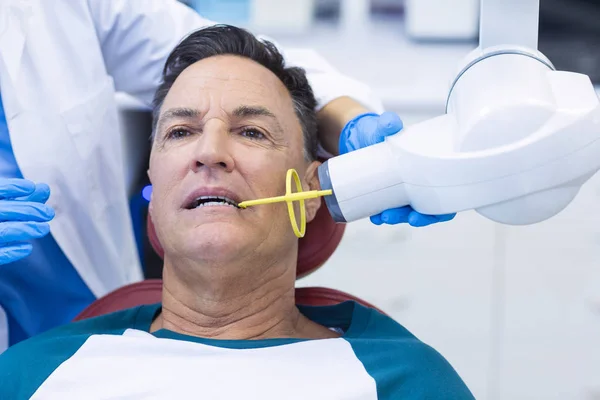 Dentiste examinant un patient masculin avec un outil — Photo