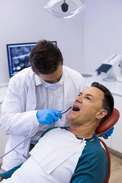 Tandarts behandeling van een mannelijke patiënt met hulpmiddelen — Stockfoto