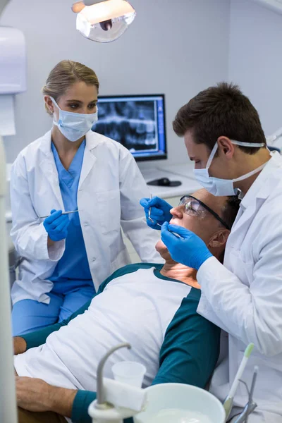 Dentists examining a male patient with tools Royalty Free Stock Photos