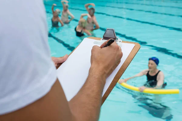 Treinador de natação escrevendo na área de transferência perto da piscina — Fotografia de Stock