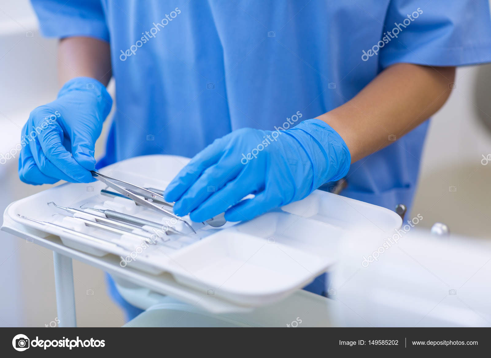 Nurse picking up dental tools from tray — Stock Photo © Wavebreakmedia