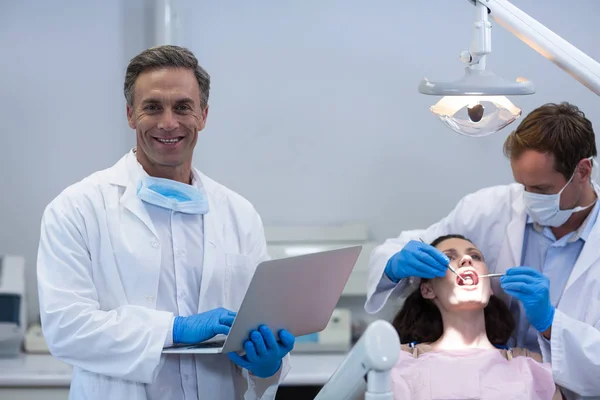 Οδοντίατρος κρατώντας το laptop στο οδοντιατρείο — Φωτογραφία Αρχείου