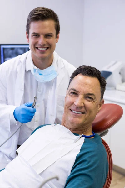 Dentist examining a male patient with tools — Stock Photo, Image