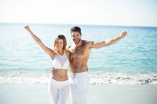 Couple debout avec les bras tendus à la plage — Photo