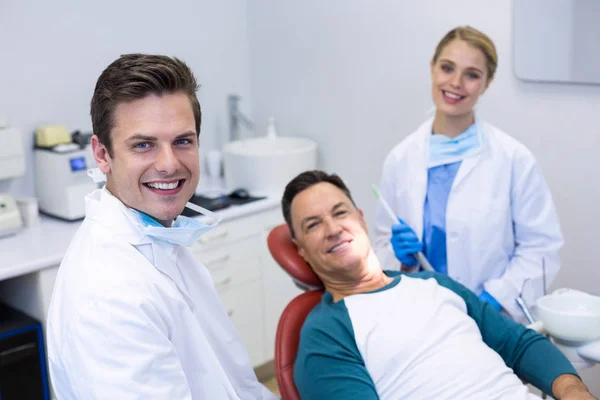 Dentistas sonrientes y paciente masculino —  Fotos de Stock